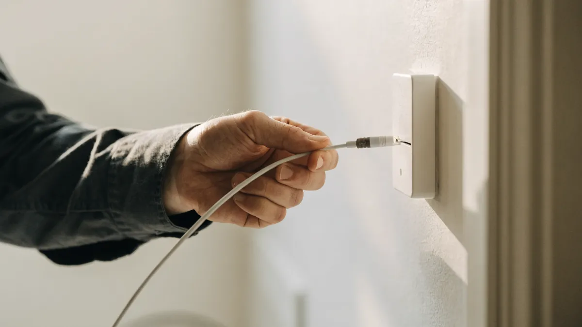 Technician connecting a fiber optic cable to a wall socket