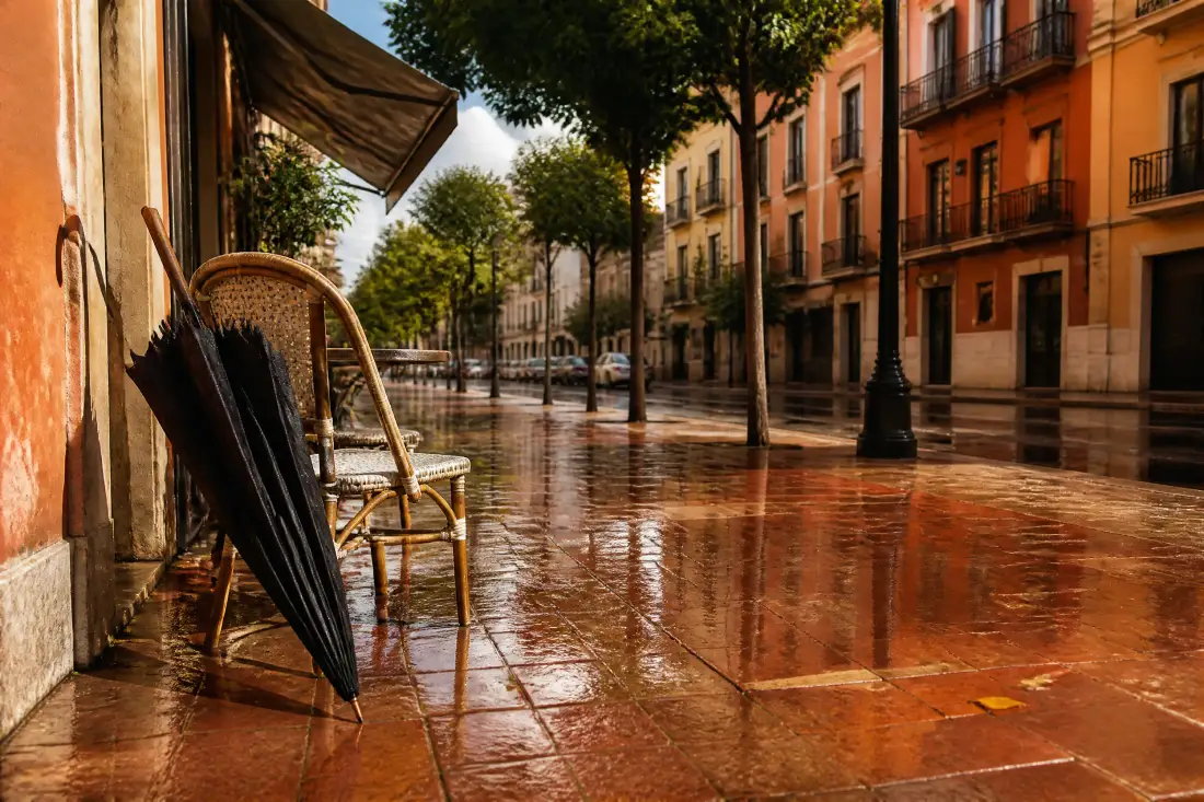 Une terrasse de café vide et détrempée avec un parapluie plié à Valencia