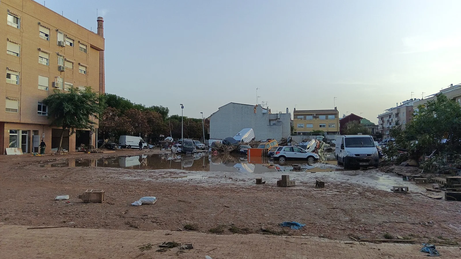 Una calle de Paiporta la mañana siguiente a la riada del 29 de octubre de 2024: barro espeso sobre la calzada, coches amontonados unos contra otros y restos acumulados junto a los edificios.