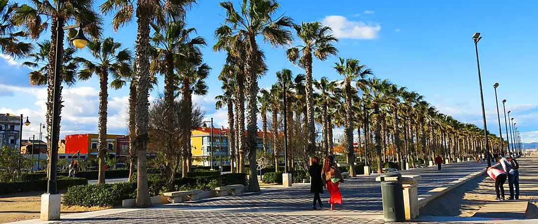 The palm-lined seafront promenade at El Cabanyal in Valencia, with low painted houses set back on one side