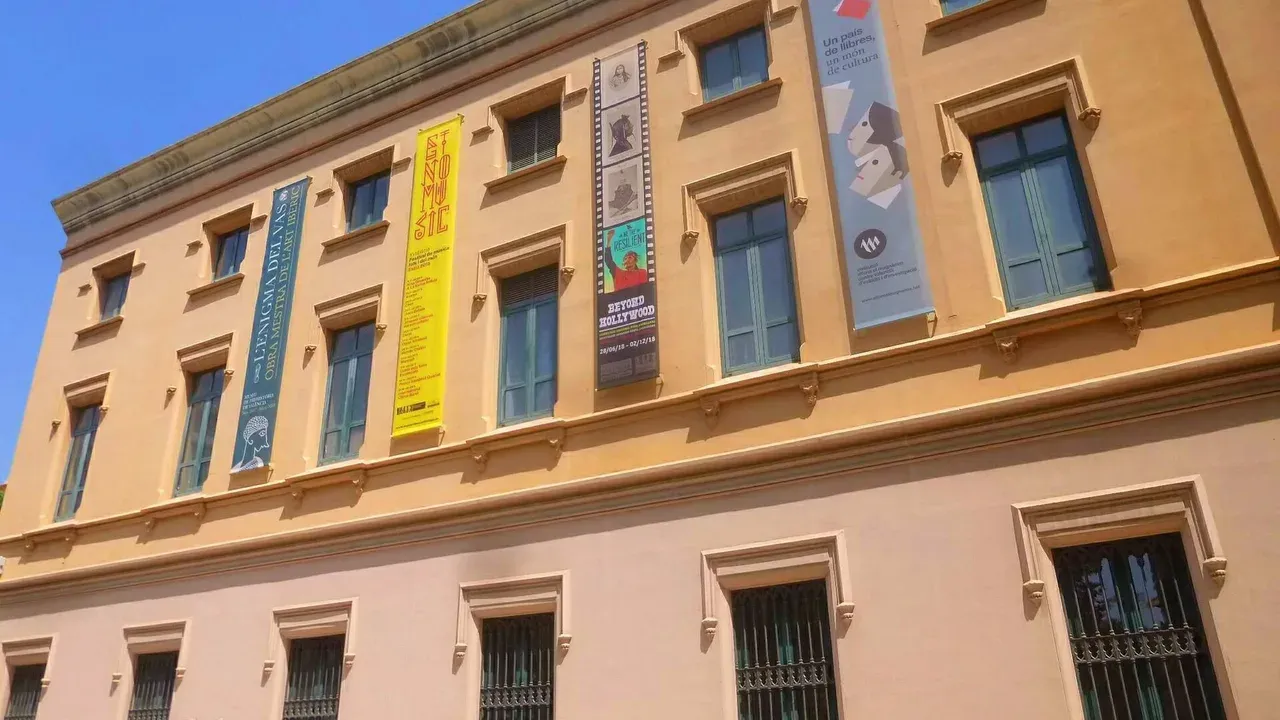 La fachada ocre del Centre Cultural la Beneficència de Valencia, con grandes pancartas de exposiciones colgadas entre las ventanas