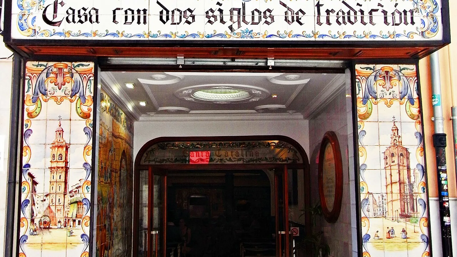 The ceramic-tiled entrance of a historic horchateria in Valencia's old town, hand-painted azulejo panels flanking the doorway