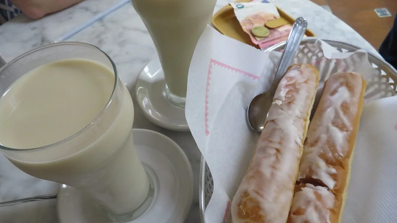 Deux verres d'horchata et une corbeille de fartons glacés au sucre sur une table de café en marbre