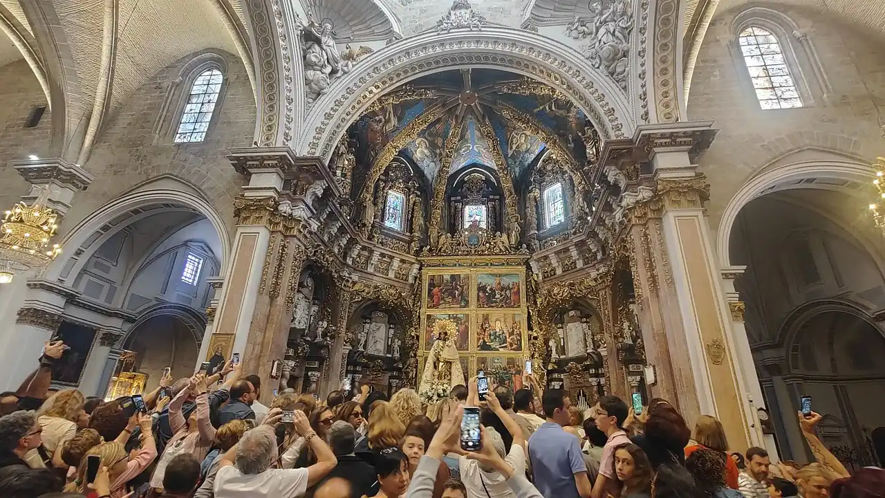 The image of the Mare de Déu dels Desemparats being carried into Valencia Cathedral during the Traslado, the crowd holding up phones under the gilded altarpiece