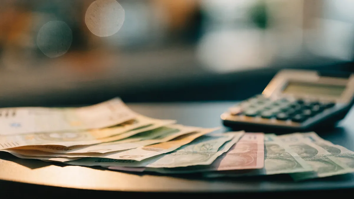 Billets en euros et en livres déployés en éventail à côté d'une calculatrice