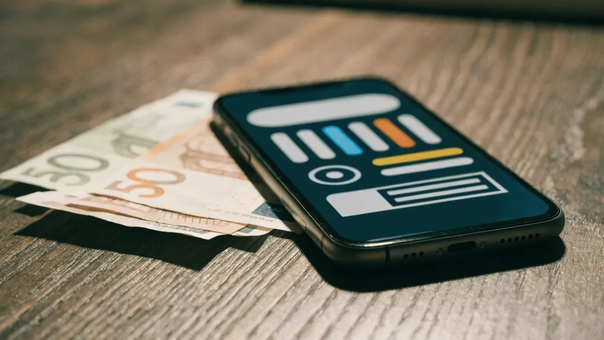 Téléphone avec une application de transfert d'argent à côté de billets en euros