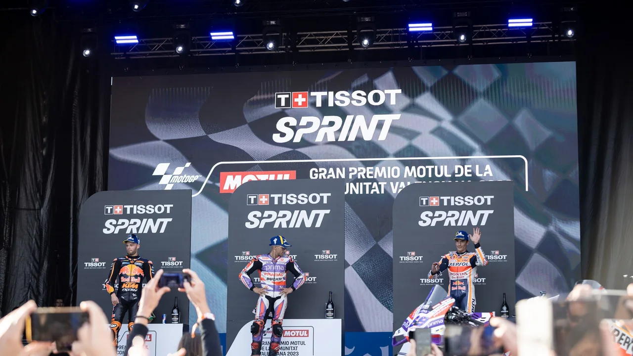 Trois pilotes sur le podium du Tissot Sprint au Grand Prix de la Communauté valencienne 2023, avec au premier plan des spectateurs qui lèvent leur téléphone