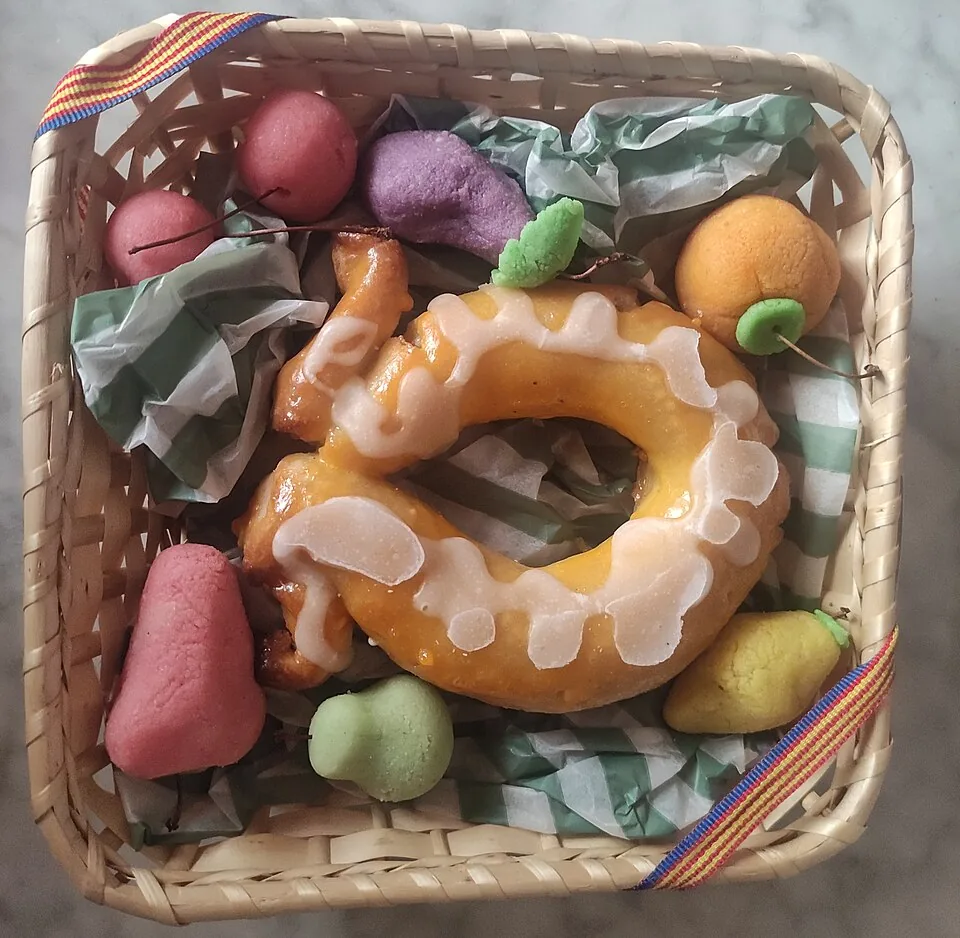 Vierkante rieten mand met een geglazuurd ringvormig gebak en marsepeinen fruit, vastgebonden met een lint in de rode en gele strepen van de Valenciaanse vlag