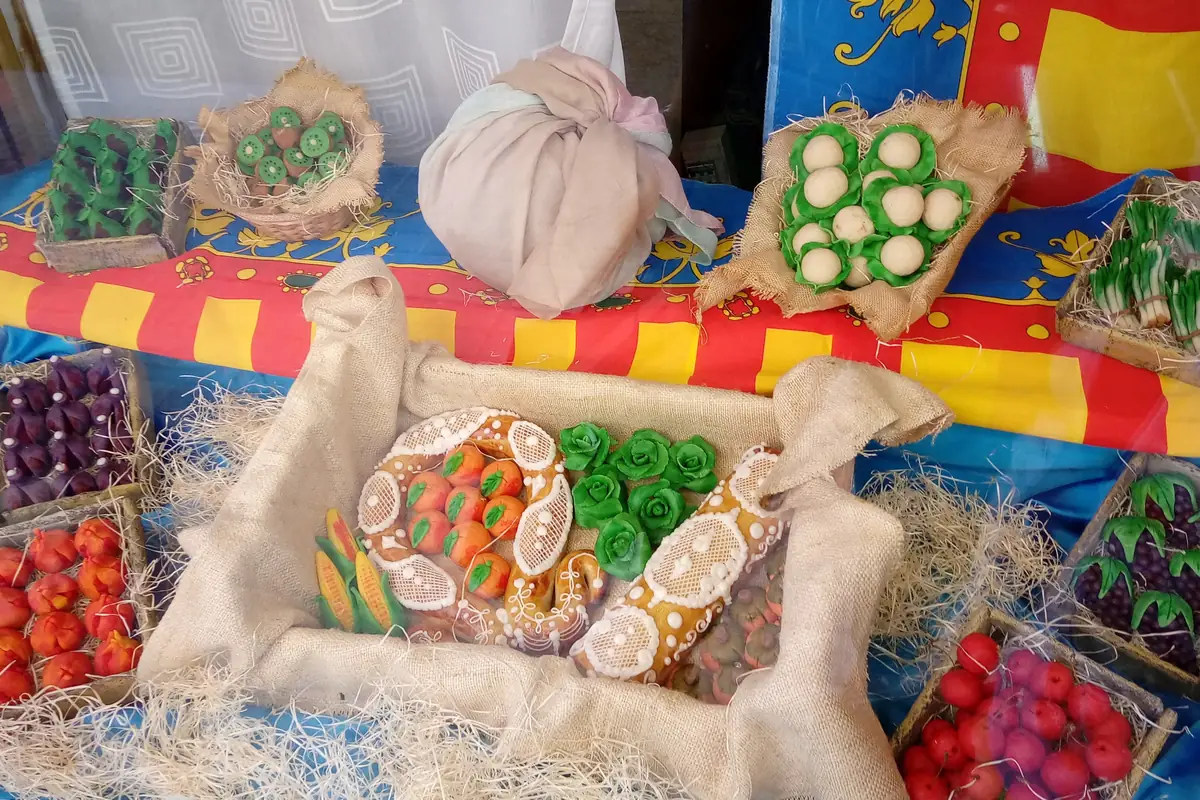 Escaparate de una panadería de Valencia con frutas de mazapán para la mocadorà colocadas sobre paja dentro de una caja, con un pañuelo de seda anudado encima