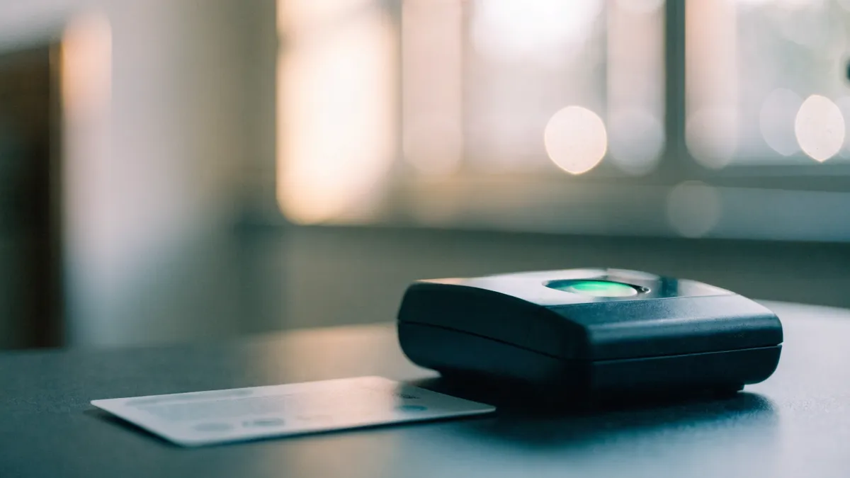 Generic biometric residence card beside a fingerprint scanner