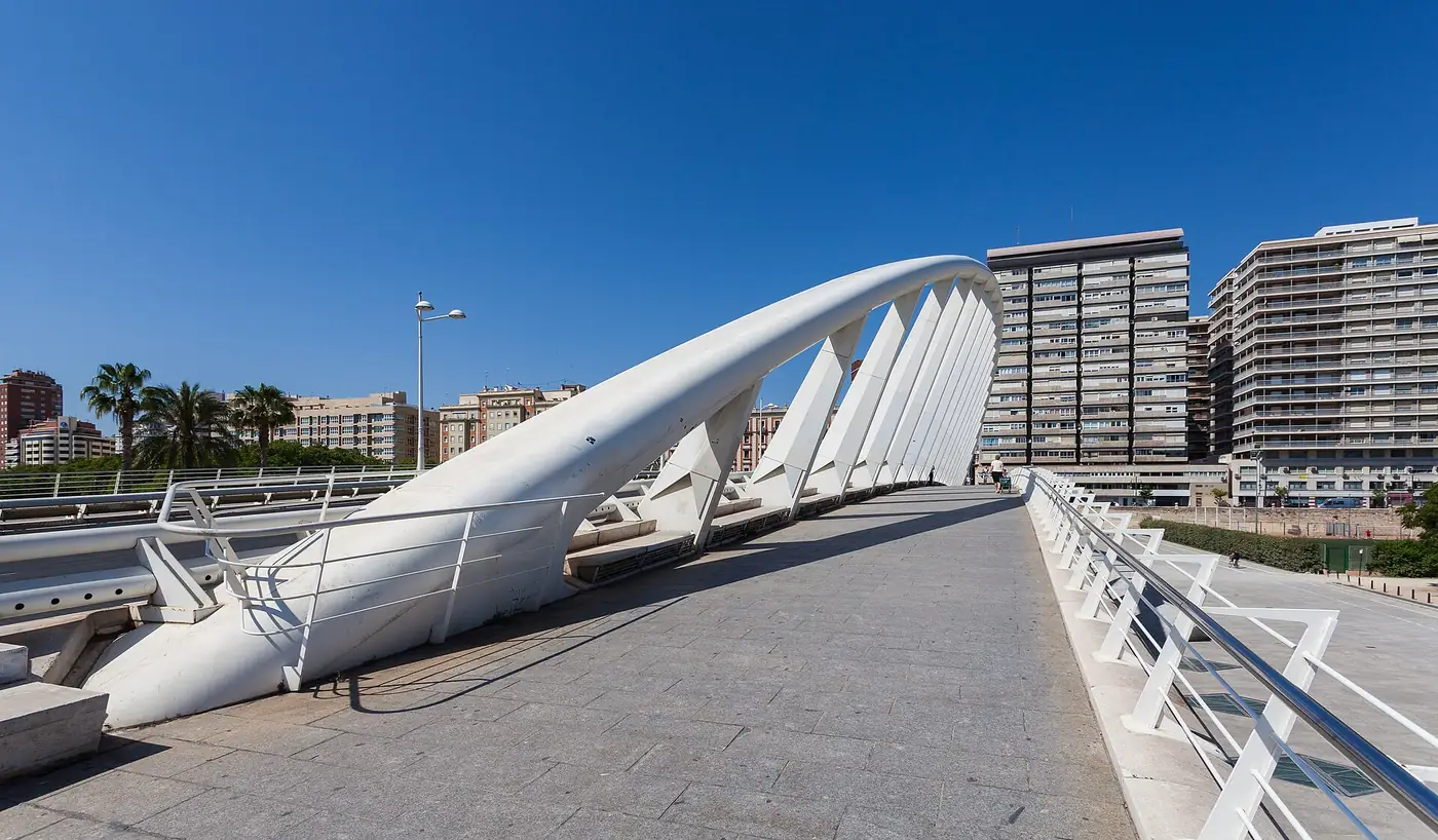 L'arc blanc en acier du Pont de l'Exposicio, surnommé la peineta, traversant les Jardins du Turia avec des immeubles en arrière-plan