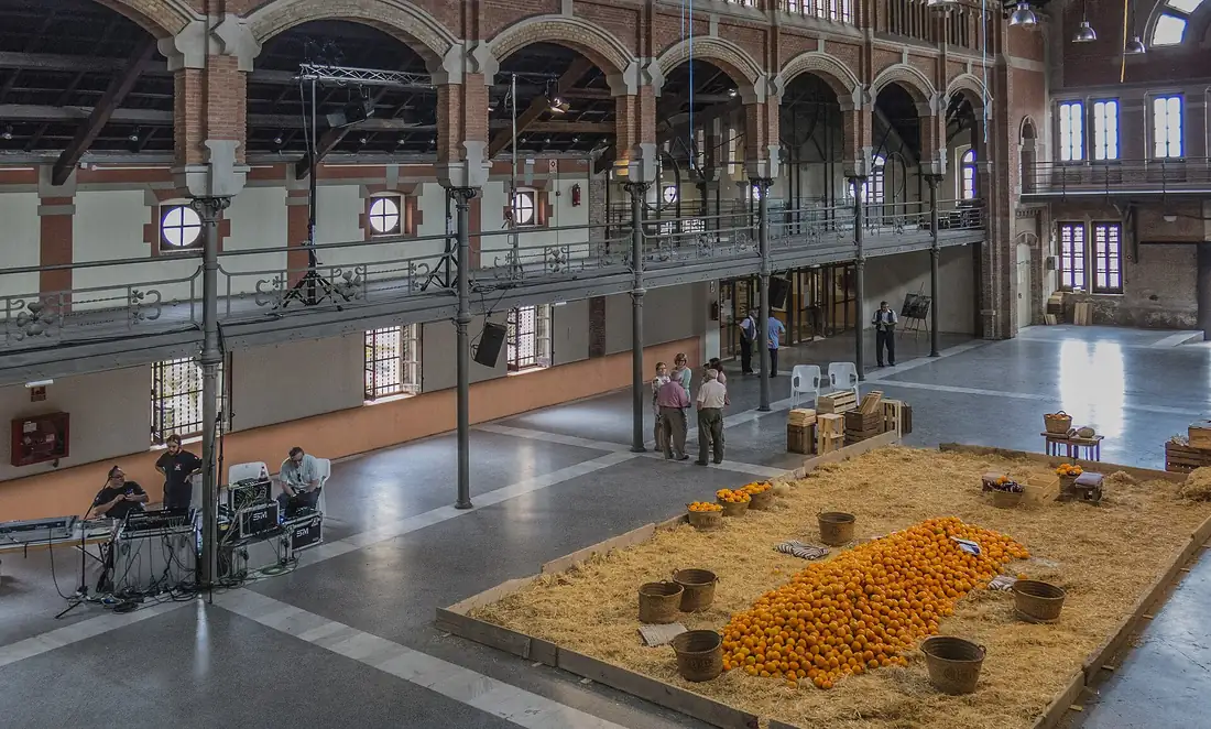 Interior of the Magatzem de Ribera, a modernist citrus packing warehouse in Carcaixent, with crates and baskets of oranges piled on straw