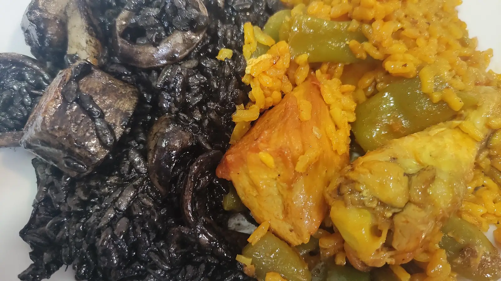 Un plato con arroz negro de tinta de sepia a un lado y paella al otro