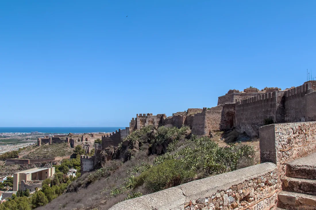 Les remparts et les tours du château de Sagunto courant sur la crête au-dessus de la ville, la Méditerranée au loin