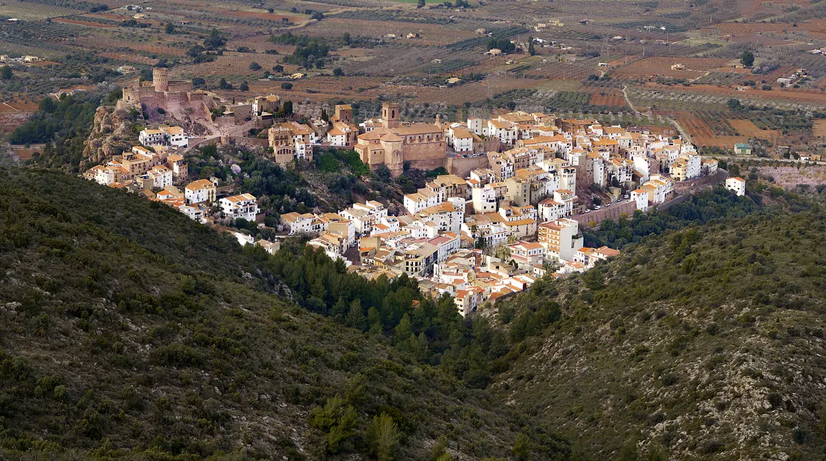 Vilafamés sur sa colline, le château à l'extrémité gauche de la crête, vu depuis l'autre côté d'une vallée boisée