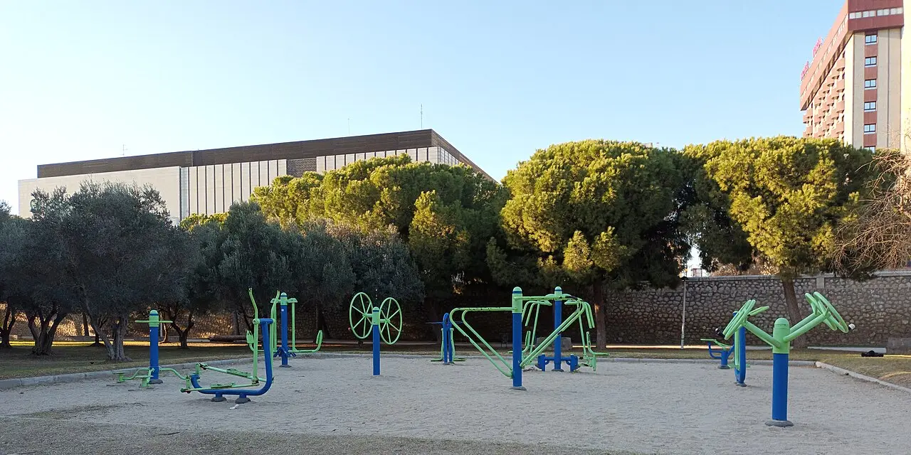 El gimnasio al aire libre del Jardín del Turia en Valencia, con aparatos azules y verdes bajo los pinos piñoneros