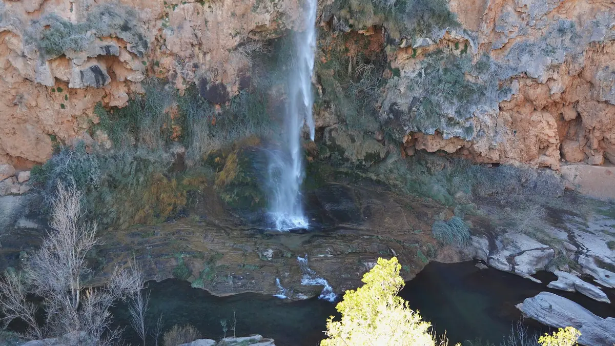 La cascada del Salto de la Novia cayendo en una poza bajo una pared de roca ocre en Navajas