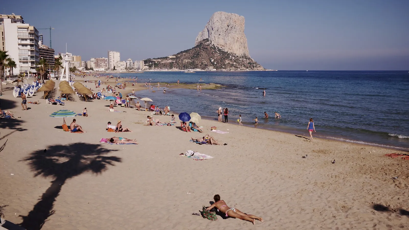 La plage d'Arenal-Bol à Calpe, avec des baigneurs sur le sable fin, des immeubles en front de mer et le rocher du Penyal d'Ifac au fond