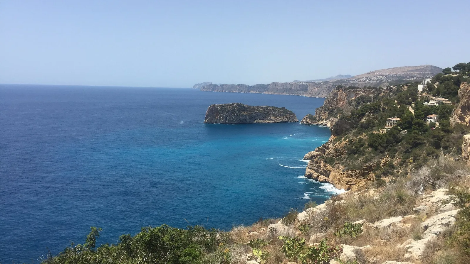 Acantilados y un islote frente al Cap de la Nau en Xàbia, con la costa hacia el sur
