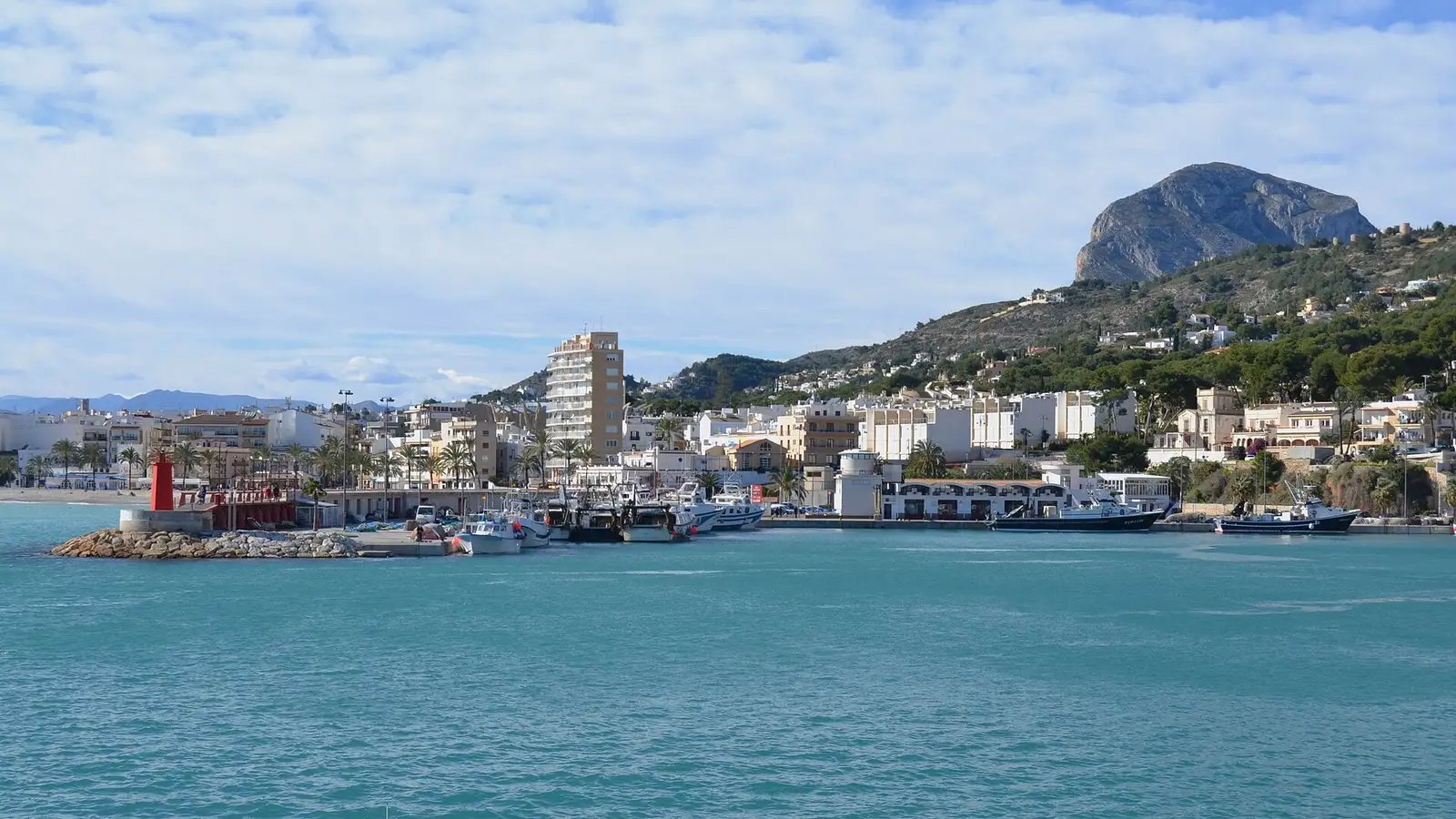 Le port de Xàbia avec ses bateaux de pêche et son feu rouge, et le Montgó derrière la ville