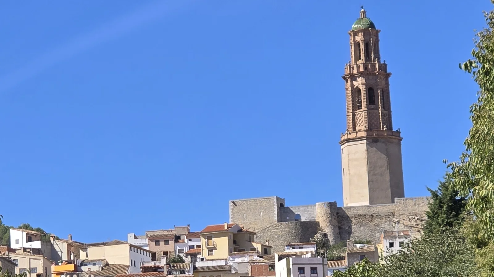 The brick Mudéjar bell tower of Jérica rising above the stone castle walls and the top of the old town