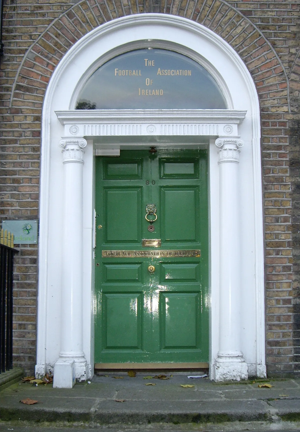 A colourful green Georgian front door in Dublin, framed by white pillars