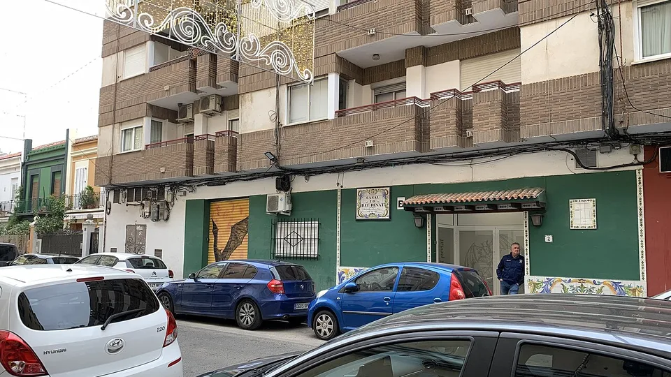 Un coin de rue avec le casal de la Falla Illes Canàries-Lo Rat Penat au rez-de-chaussée d'un immeuble de brique et des maisons basses plus loin, à Camí Fondo, Valencia