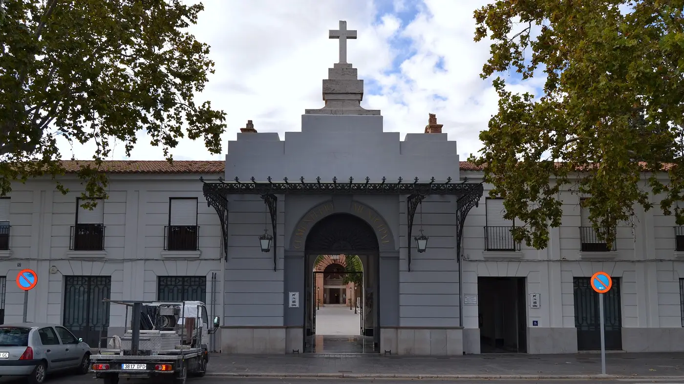 La porte principale du cimetière municipal de Valencia, un portail gris surmonté d'une croix entre deux longues ailes, à Camí Reial, Valencia