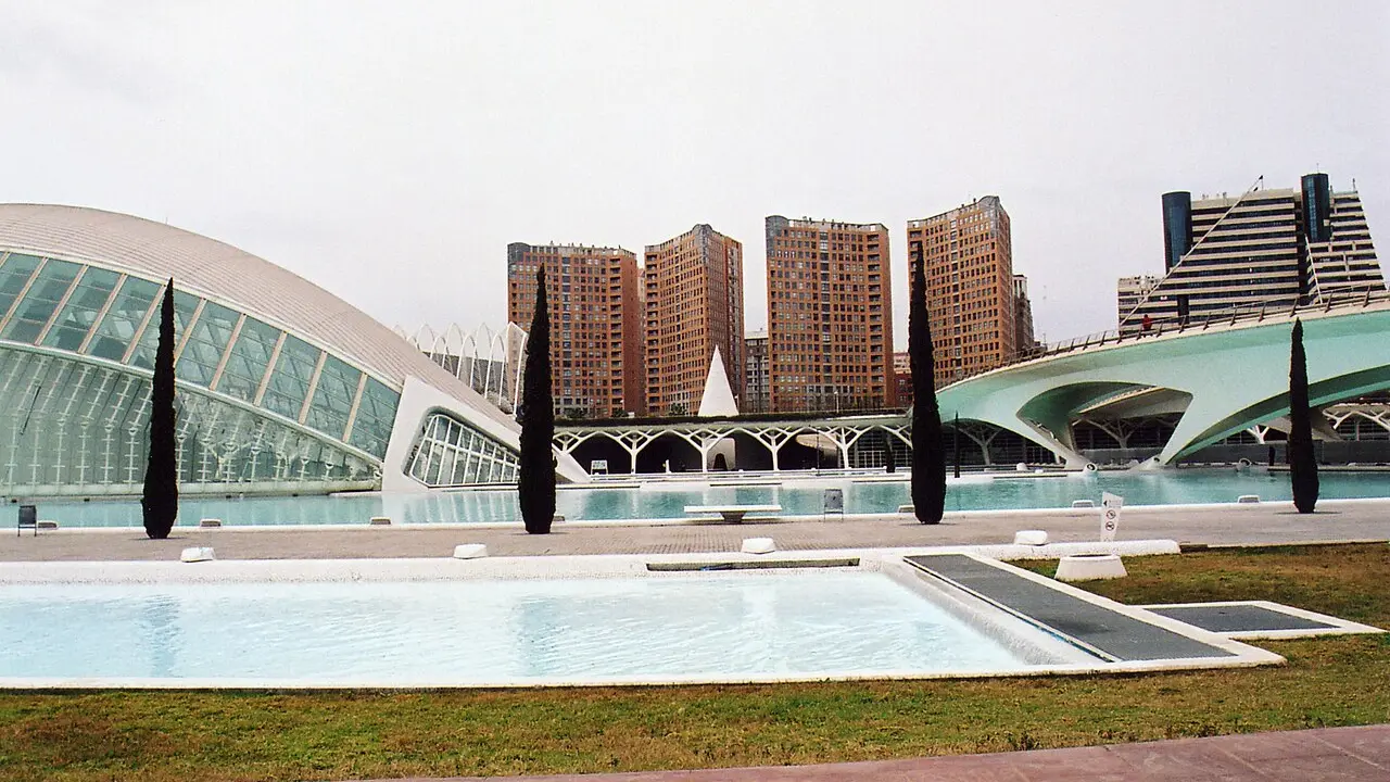 L'Hemisfèric et l'Umbracle au bord de leurs bassins, avec des tours d'habitation derrière, à Ciutat de les Arts i les Ciències, Valencia