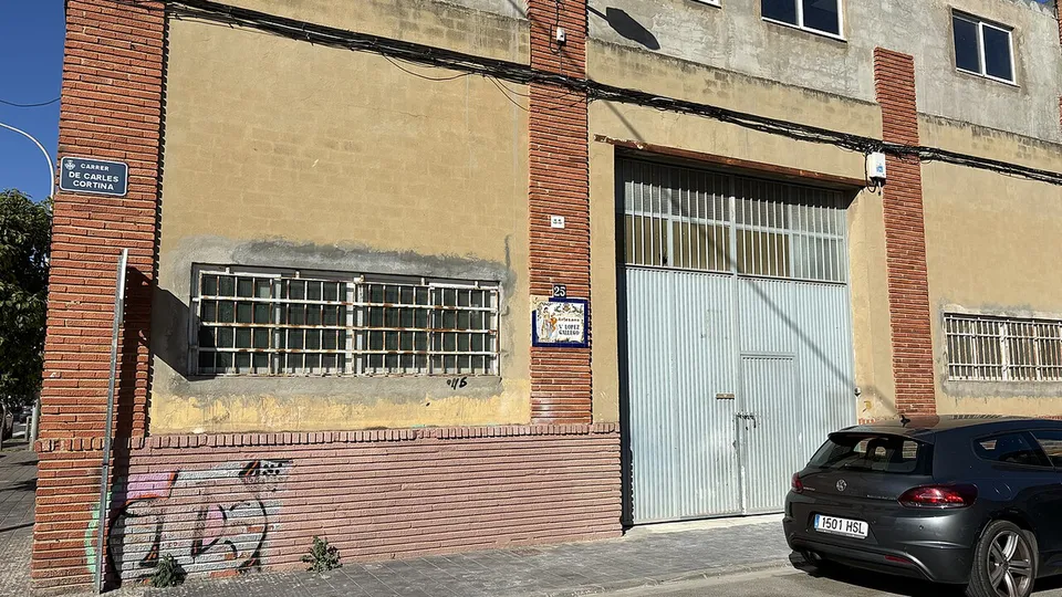 Een werkplaats van een falla-kunstenaar met een grote roldeur in een straat met werkplaatsen, in Ciutat Fallera, Valencia