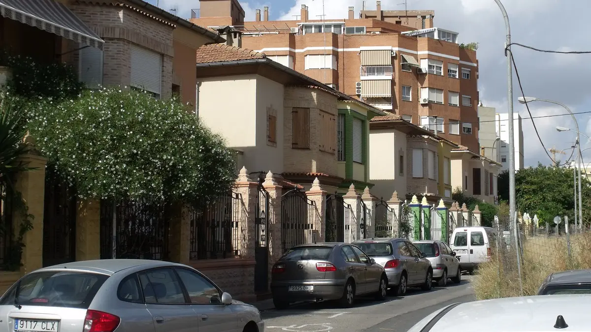 Une rangée de maisons à deux niveaux avec toits de tuiles et grilles en fer, Carrer de Ramón de Perellós à Favara, Valencia, devant un immeuble en brique