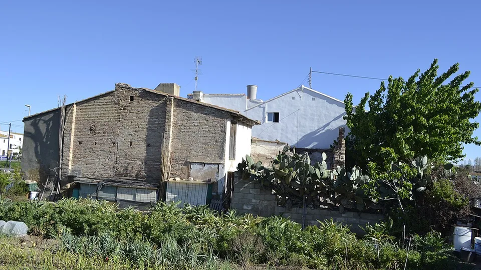 Een oude gewitte alqueria achter een akker in de huerta van La Carrasca, Valencia