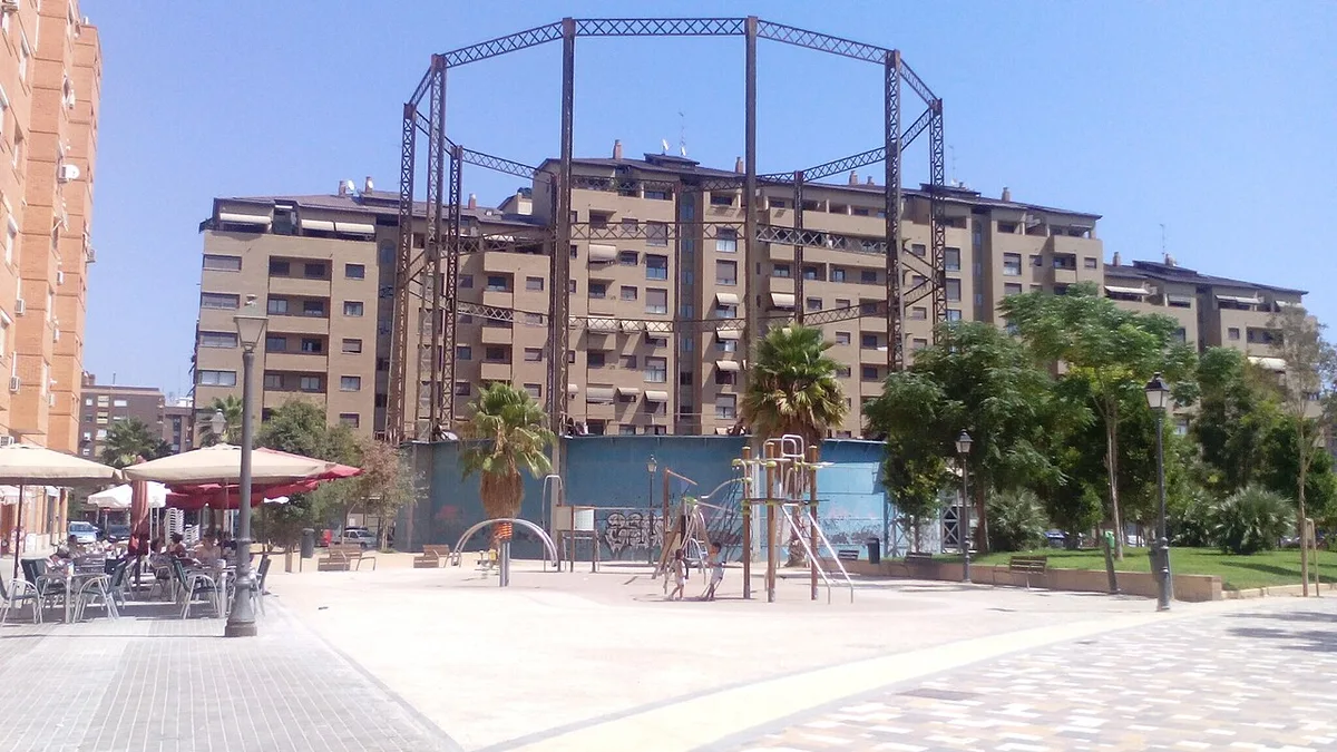 La structure en fer de l'ancien gazomètre de Gas Lebon au-dessus d'une aire de jeux et d'une nouvelle place, devant des immeubles, à La Creu del Grau, Valencia