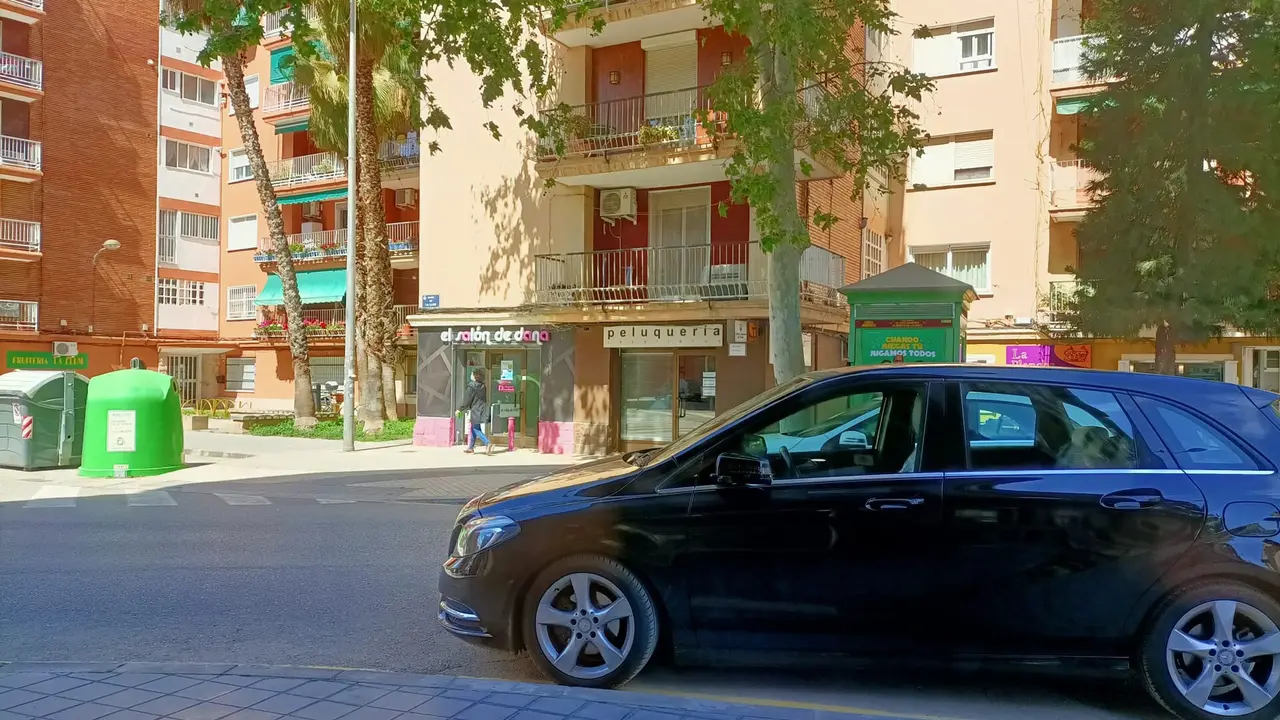 Une rue résidentielle de La Llum, à Valencia, avec des immeubles de brique et crème, des palmiers et des commerces au rez-de-chaussée