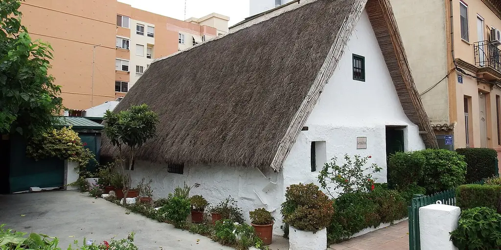 A traditional thatched barraca with a small garden, between apartment blocks in Pinedo