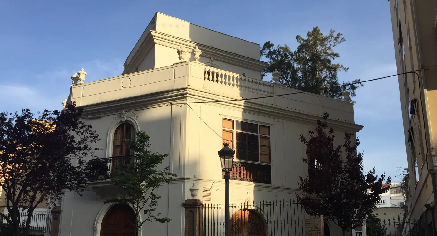 A stately historic building in Ruzafa, Valencia, lit by the golden-hour sun against a blue sky