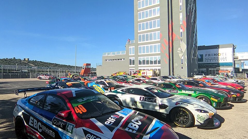 Raceauto's op een rij in de paddock voor de verkeerstoren van het Circuit Ricardo Tormo