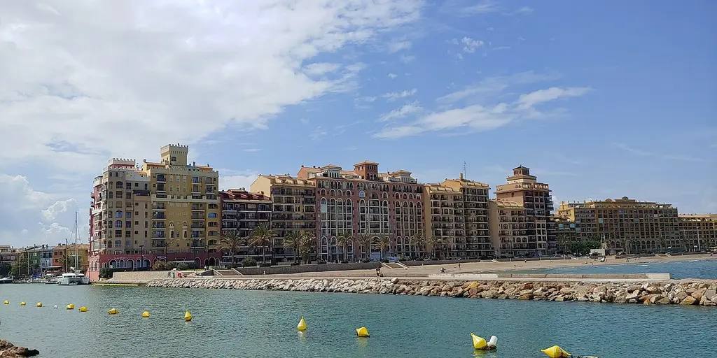 Coloured apartment blocks and moored yachts around the inner harbour at Port Saplaya in Alboraya