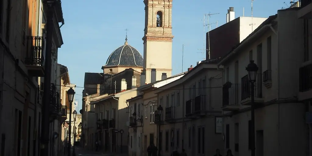 The church dome and bell tower of Godella at the end of a narrow street of older terraced houses