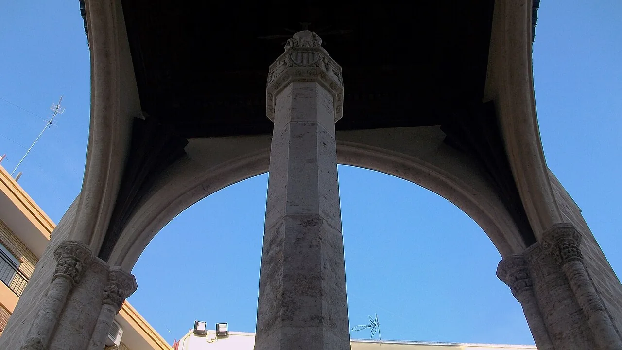 Vista hacia arriba entre los arcos góticos de la Creu Coberta, la cruz cubierta de Mislata, con su columna central