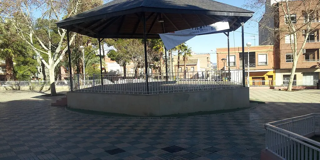 A bandstand standing in a paved, tree-lined square in Picassent