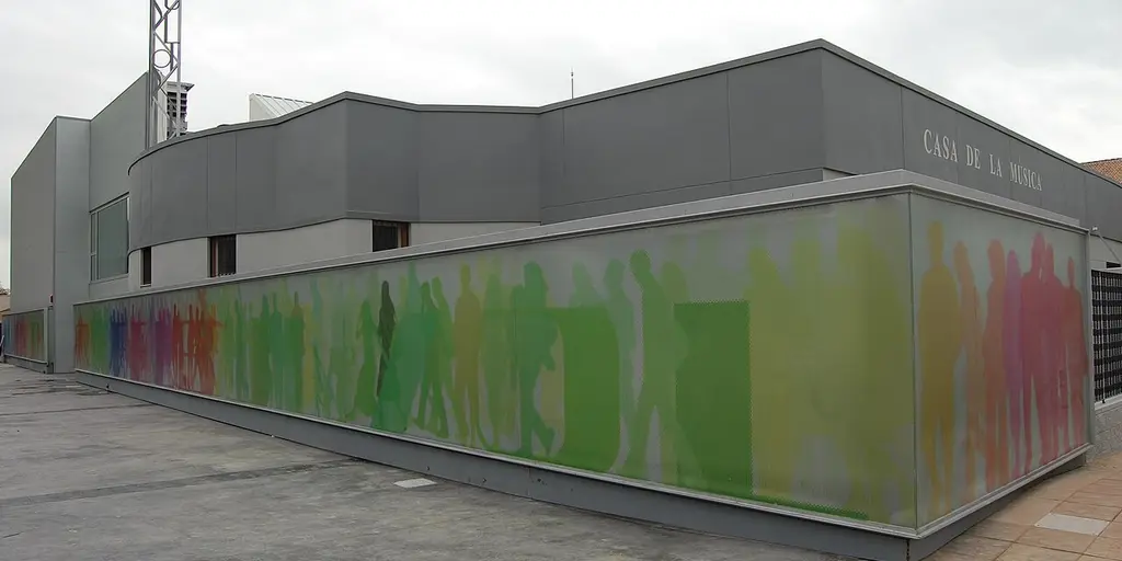 The modern municipal auditorium in Rafelbunyol, its long wall printed with a band of coloured silhouettes