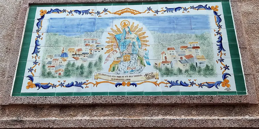 A ceramic tile panel in Serra showing the Virgin of the Angels above a painting of the village
