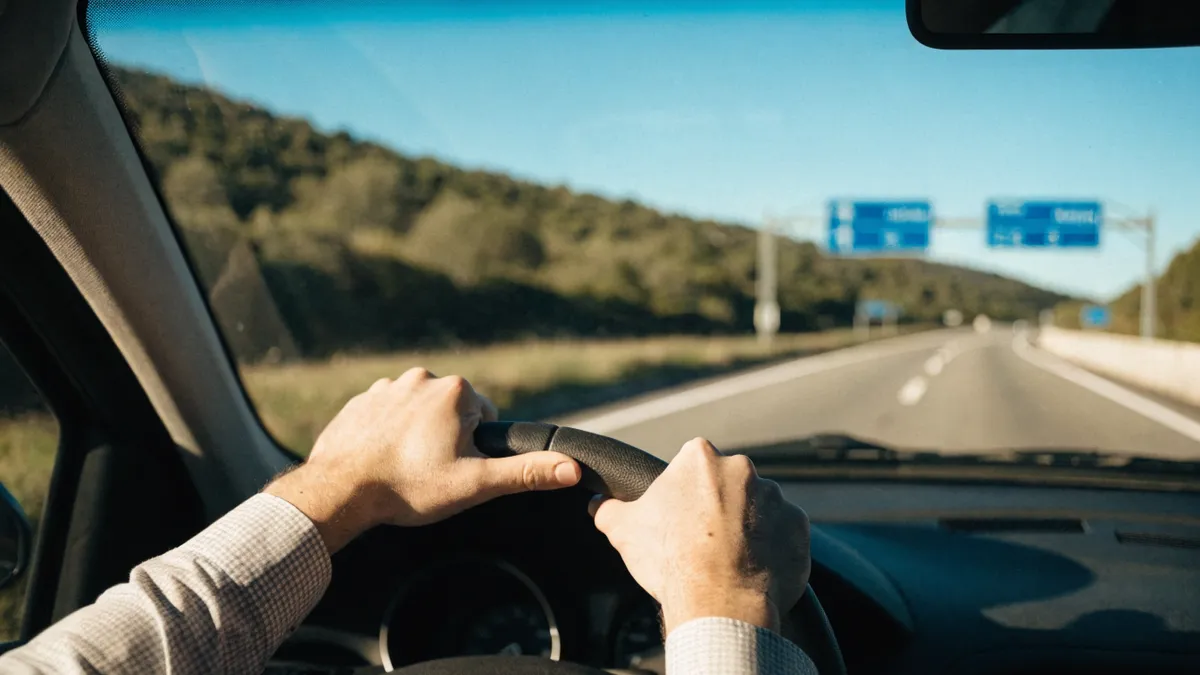 Driver's hands on the wheel with Spanish road signage ahead