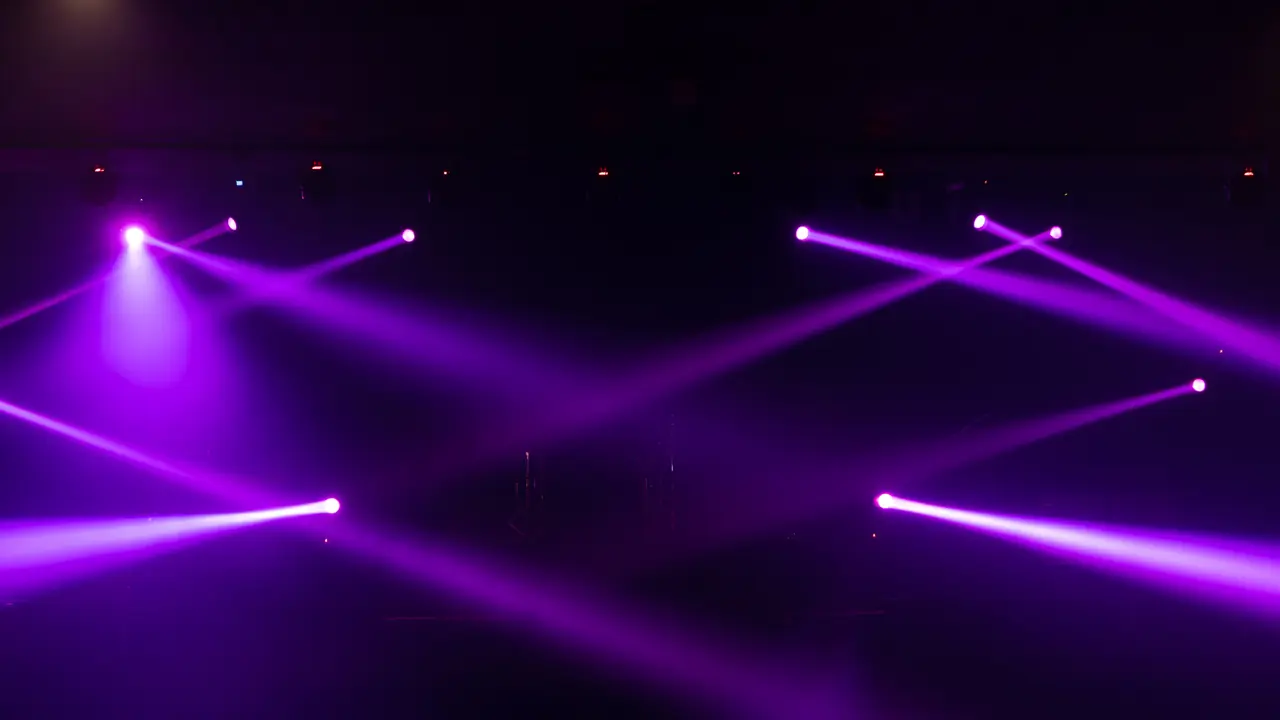 Une scène de club vide balayée par des faisceaux laser violets et des jeux de lumière