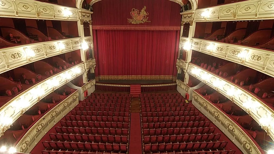 Interior of Teatre Principal in Valencia seen from above, with the red velvet curtain, gilded balconies and rows of red seats